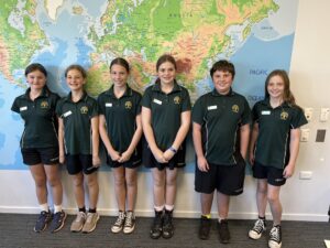 Year 7 Student council in uniform standing in front of a map